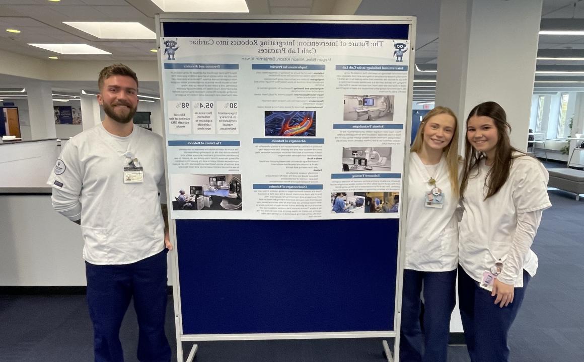 Students present poster on use of robotics in cath lab.